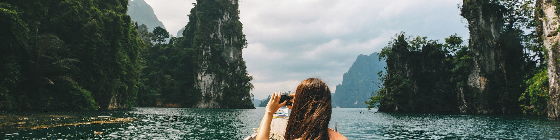 A person in a boat on a river surrounded by cliffs.