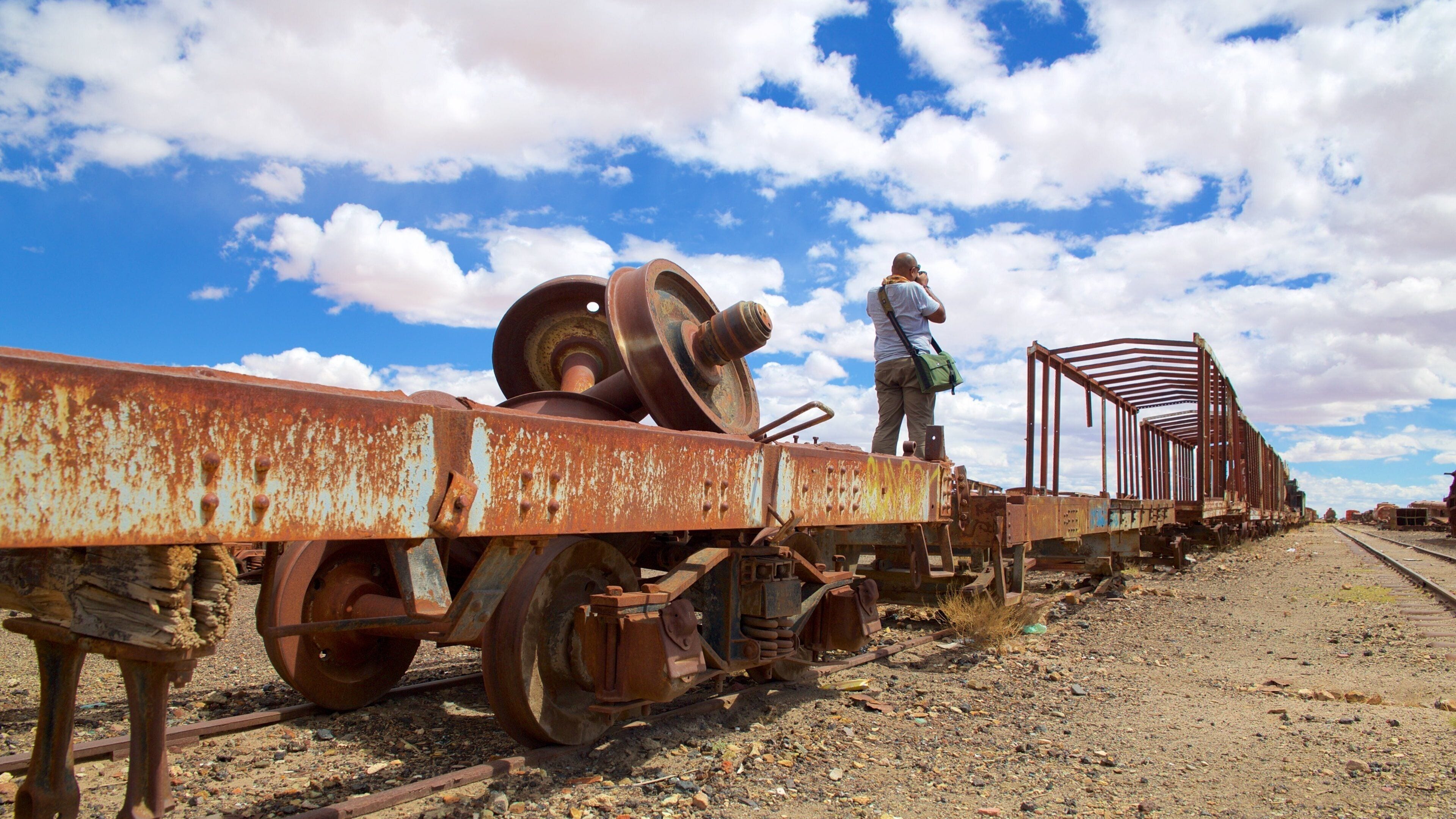 Cementerio de trenes que incluye ruinas de edificios y también un hombre