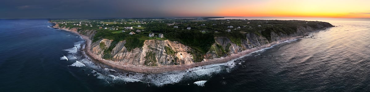 A coastal landscape with cliffs, a beach, and scattered houses.