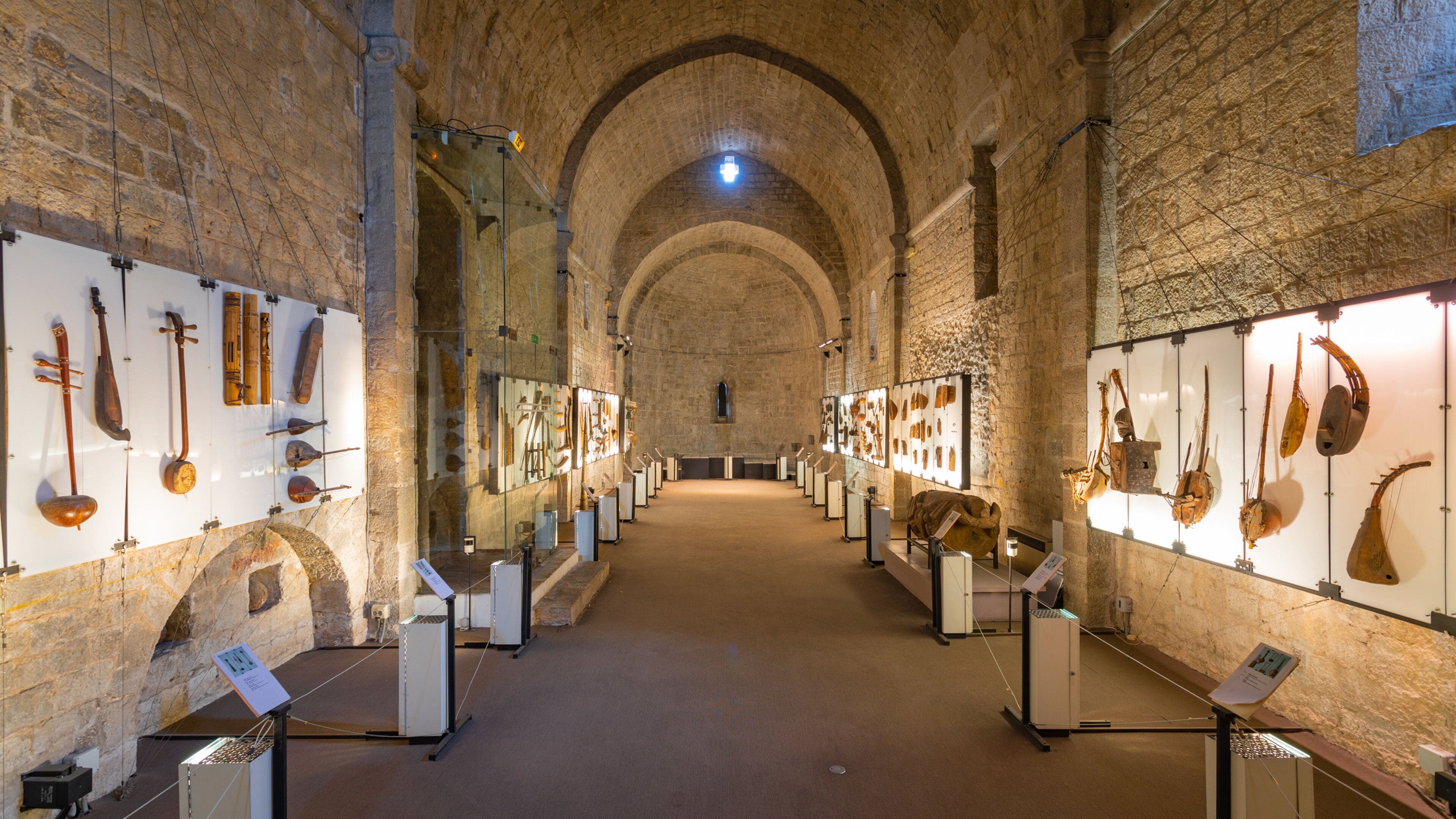 Un museo en el interior con paredes de piedra y exhibiciones de instrumentos musicales antiguos.