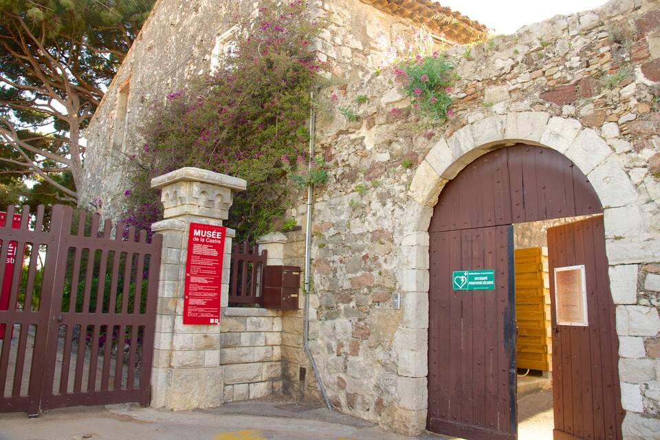 A stone building with a wooden gate and a sign for the Musée de la Castre.
