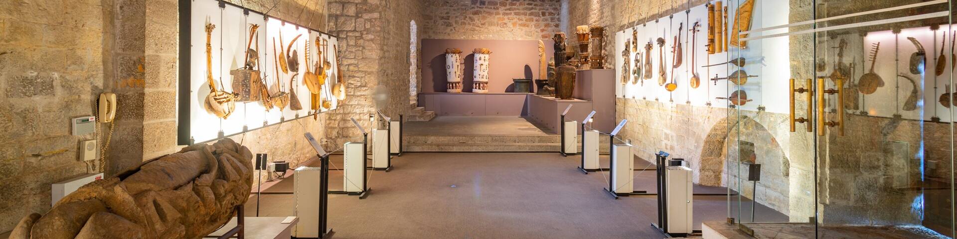 An ancient stone corridor with exhibits of historical artifacts and a large stone sculpture.