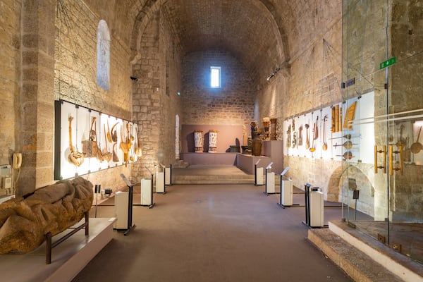 Un ancien couloir en pierre où sont exposés des objets d’art historiques et où se trouve une grande sculpture en pierre.