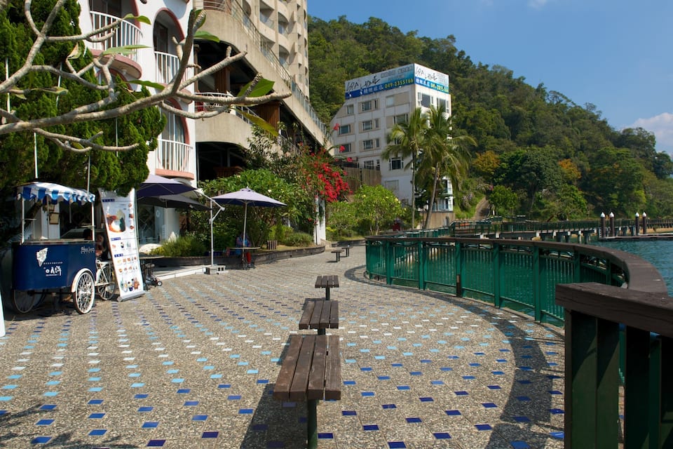 A waterfront promenade with a café, a vintage ice cream cart, and a bridge.