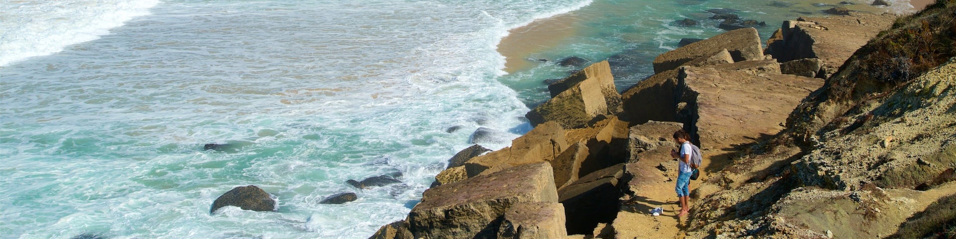 Macas Beach featuring a coastal town, a sandy beach and rocky coastline