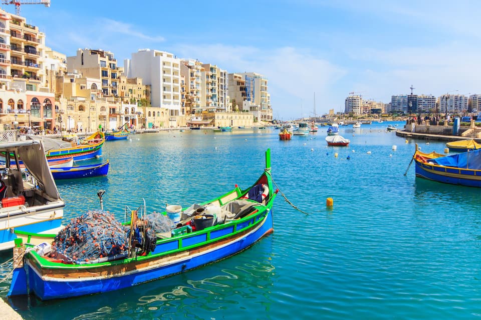 A harbor with colorful boats, buildings, and a clear blue sky.