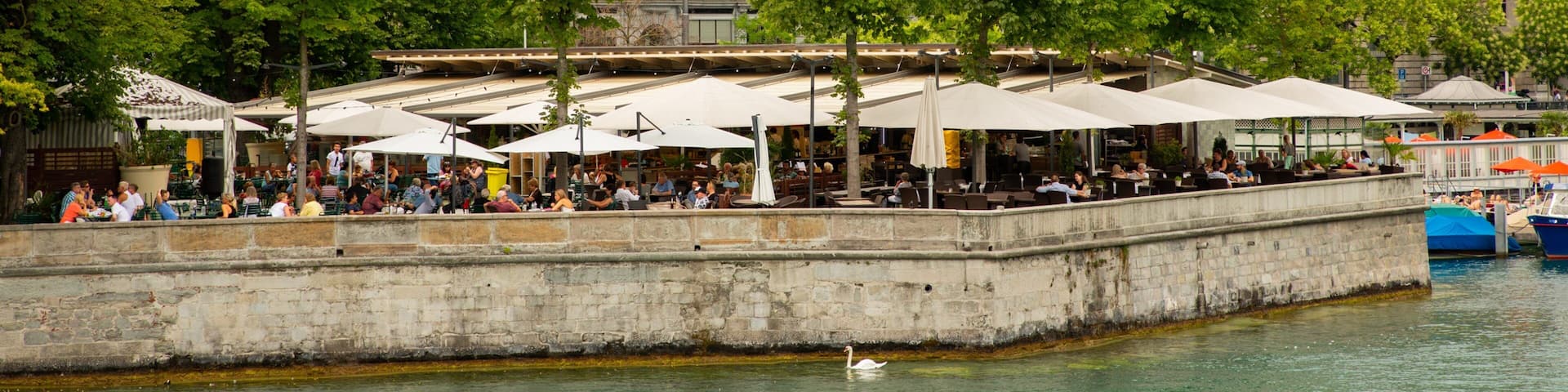Lakeside Promenade featuring outdoor eating and a river or creek as well as a large group of people