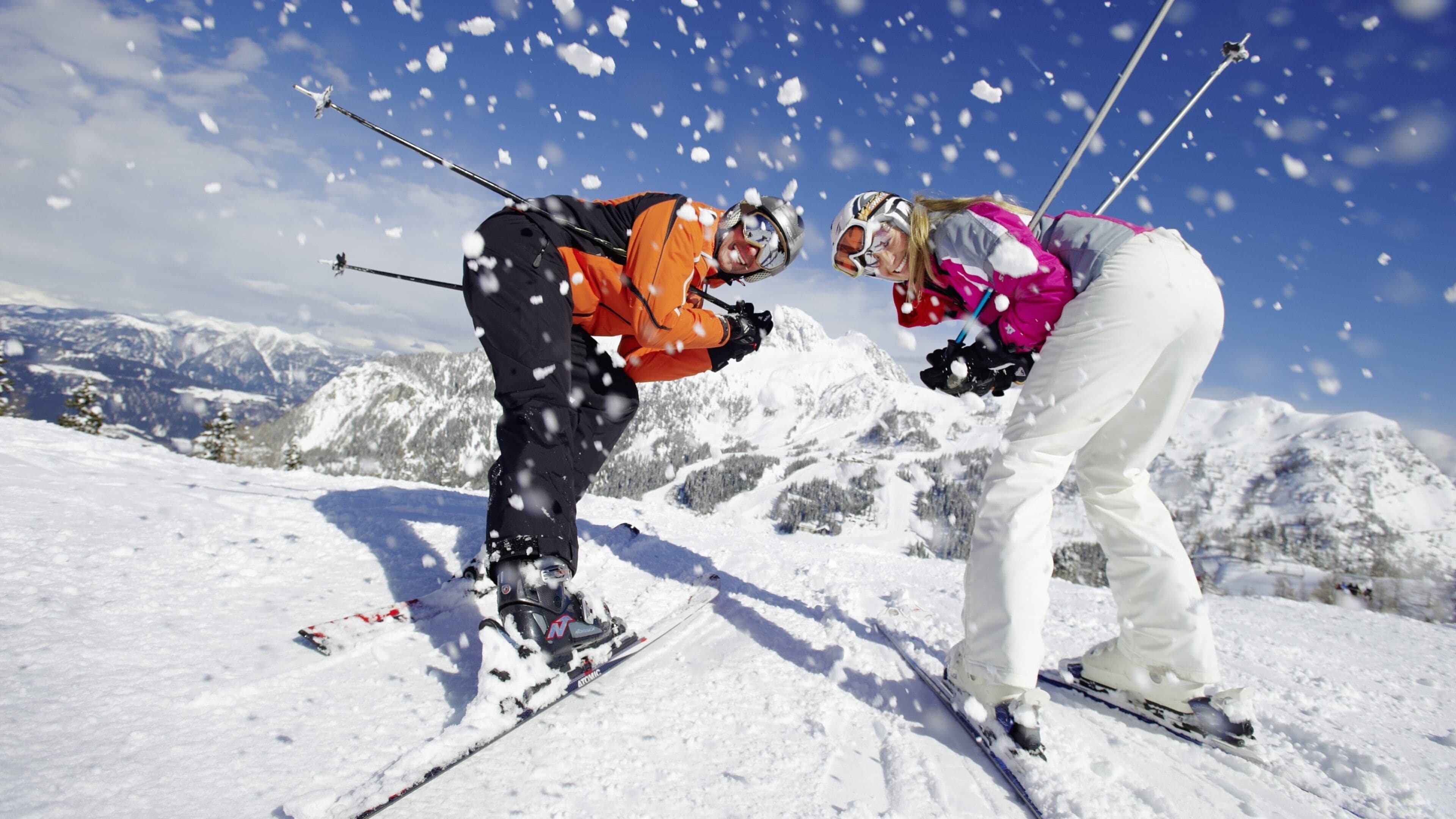 Deux skieurs sur une montagne enneigée, des flocons de neige tombent.