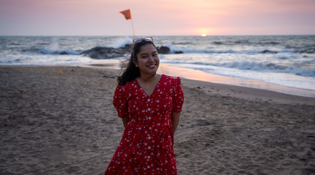 Happy beautiful young Indian woman smiling & relaxing at the Goa beach. Delightful girl enjoying Sunset at beach - Healthy lifestyle concept with female laughing.