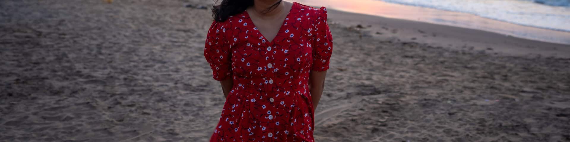 Happy beautiful young Indian woman smiling & relaxing at the Goa beach. Delightful girl enjoying Sunset at beach - Healthy lifestyle concept with female laughing.