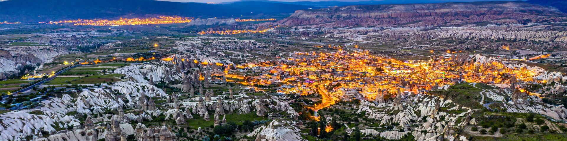 Un paisaje urbano con un terreno rocoso y escarpado y una cadena montañosa distante.