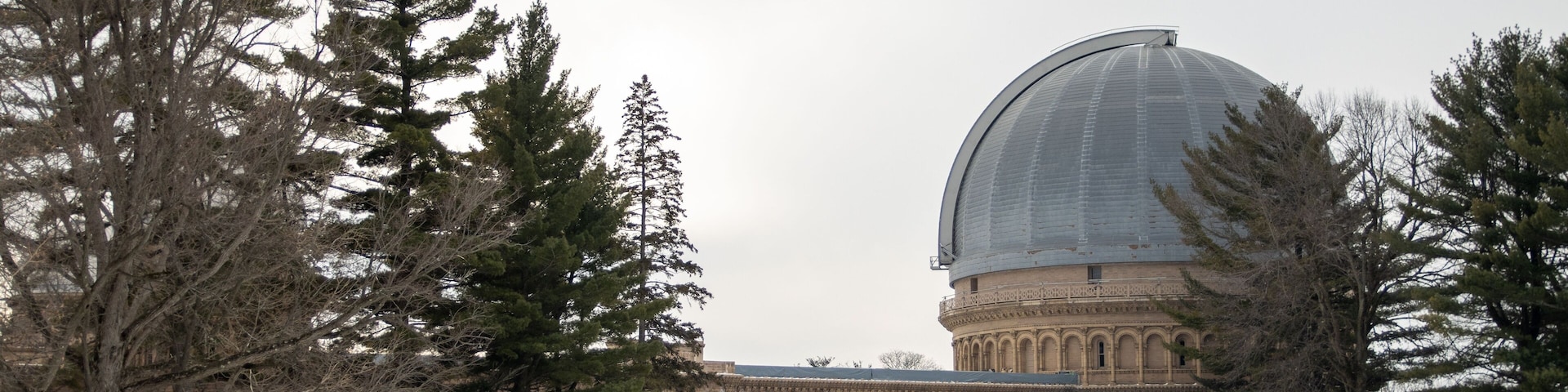 A large building with a dome and arched windows, surrounded by snow and trees.