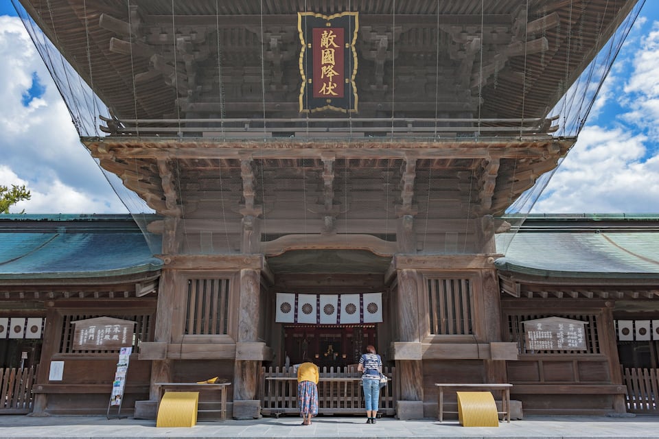 Un templo japonés tradicional con una amplia entrada de madera y un letrero con caracteres japoneses.