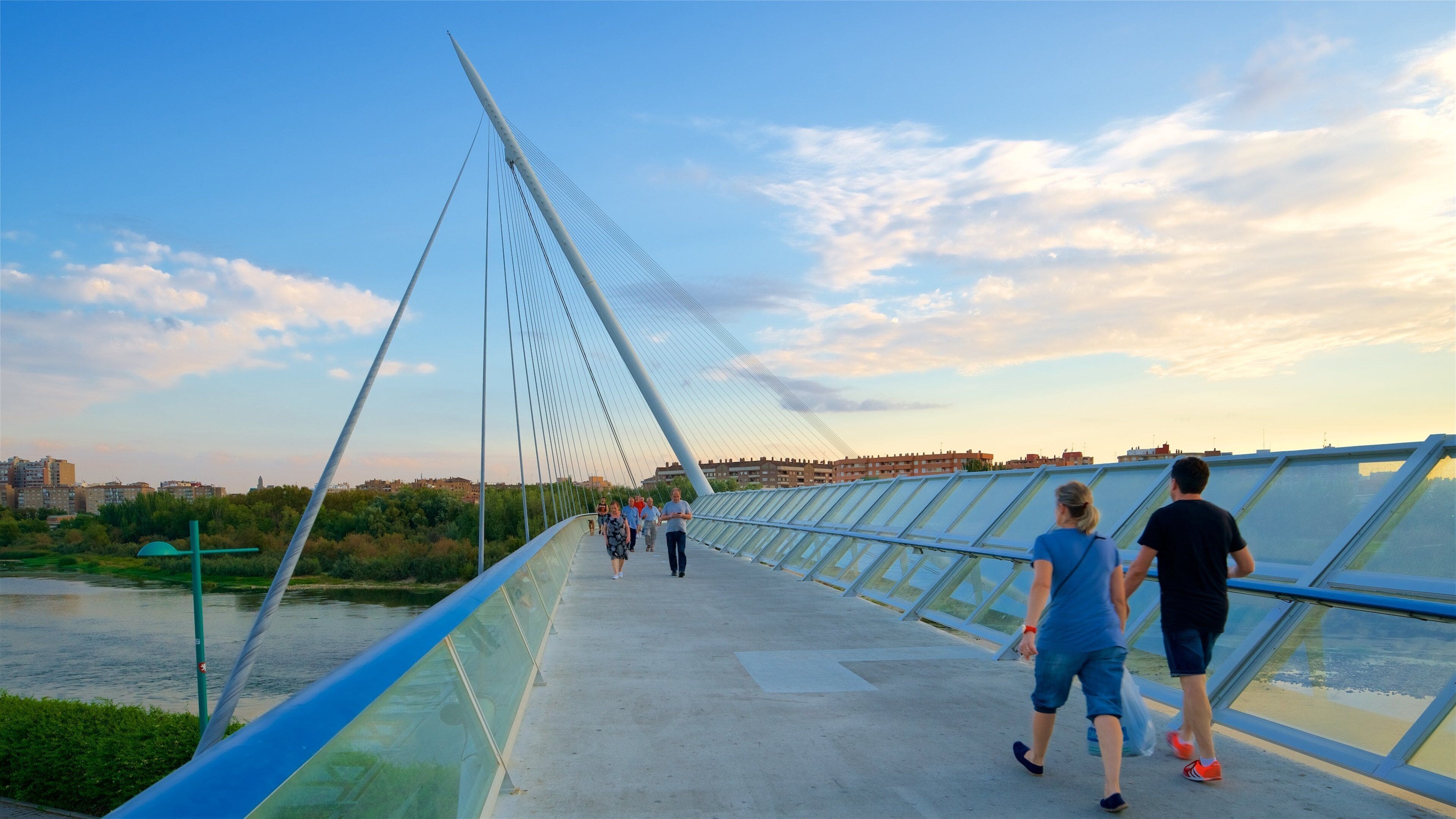 A pedestrian bridge with a glass walkway and a river below.