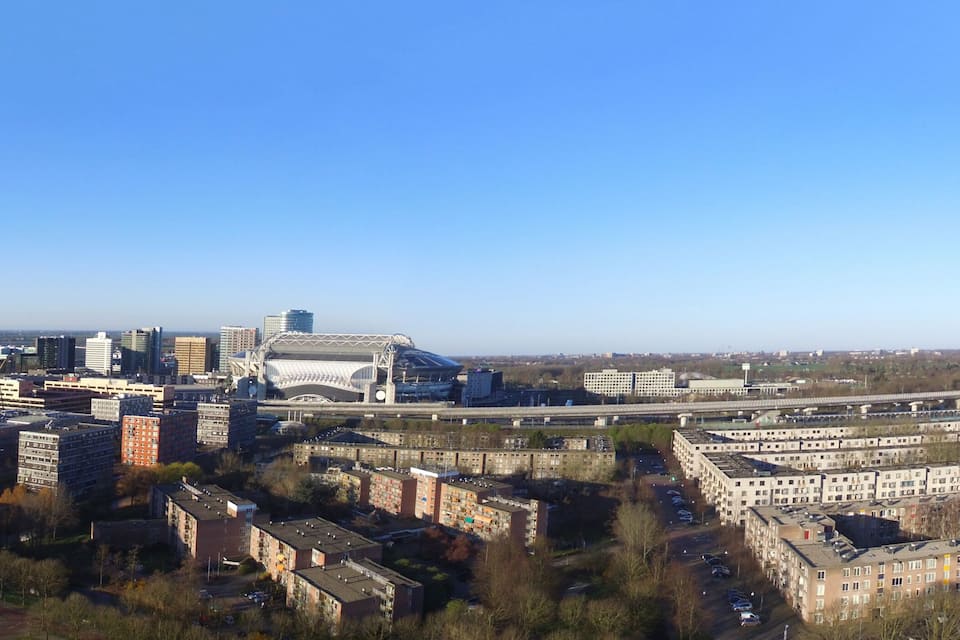 Un paisaje urbano con edificios modernos, un estadio grande y un puente.