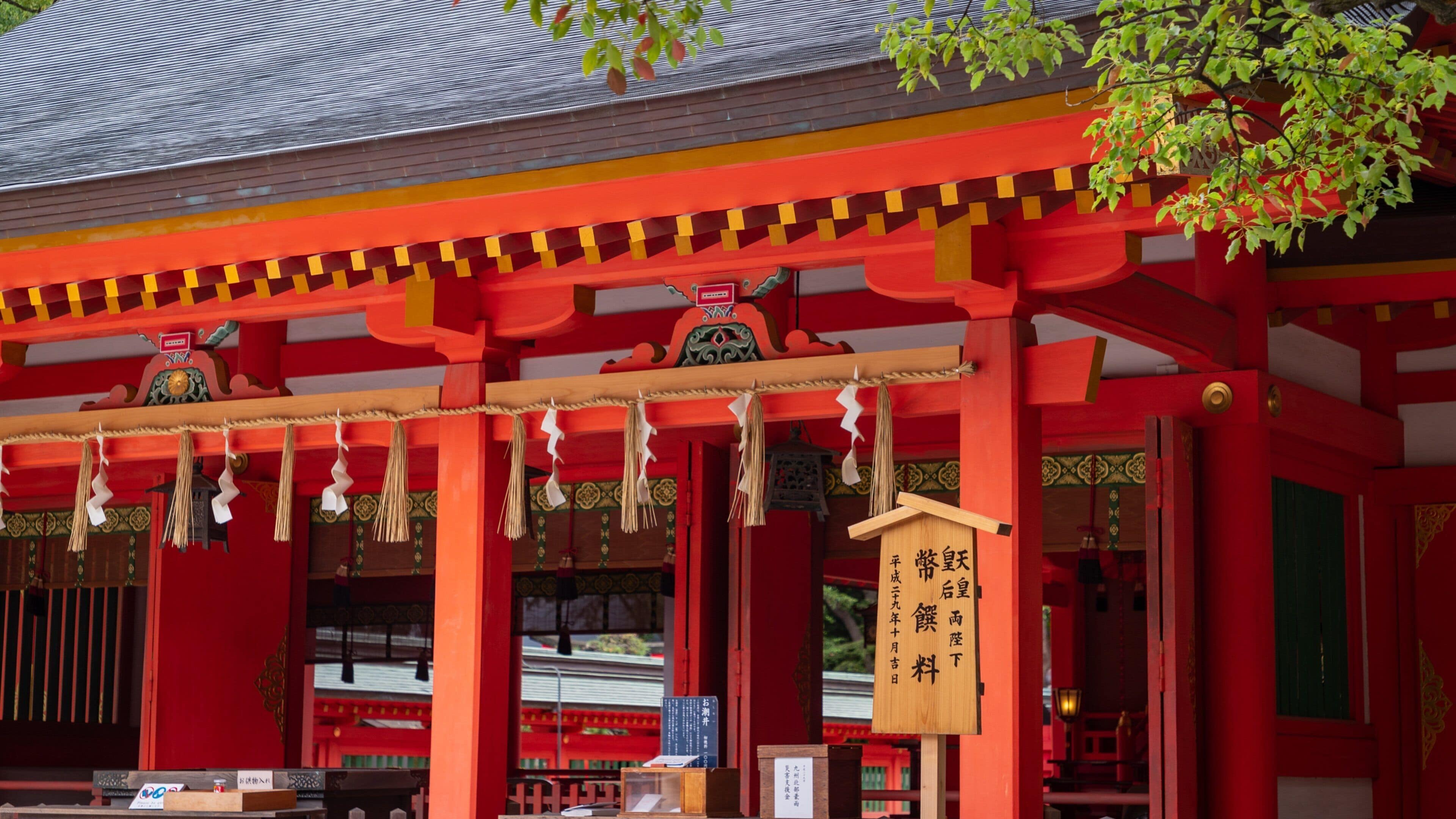 A traditional Japanese building with red pillars and a wooden sign with Japanese characters.