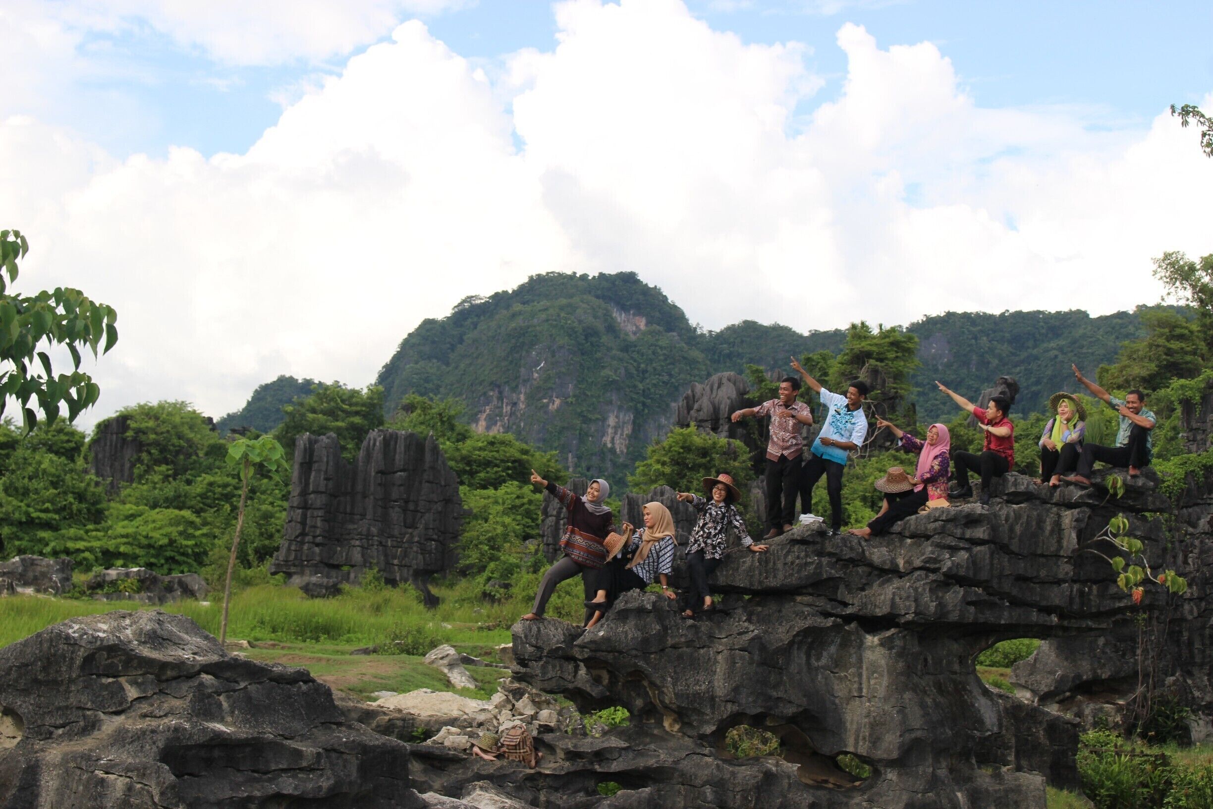 A group of people on a rocky outcrop with a mountainous landscape in the background.