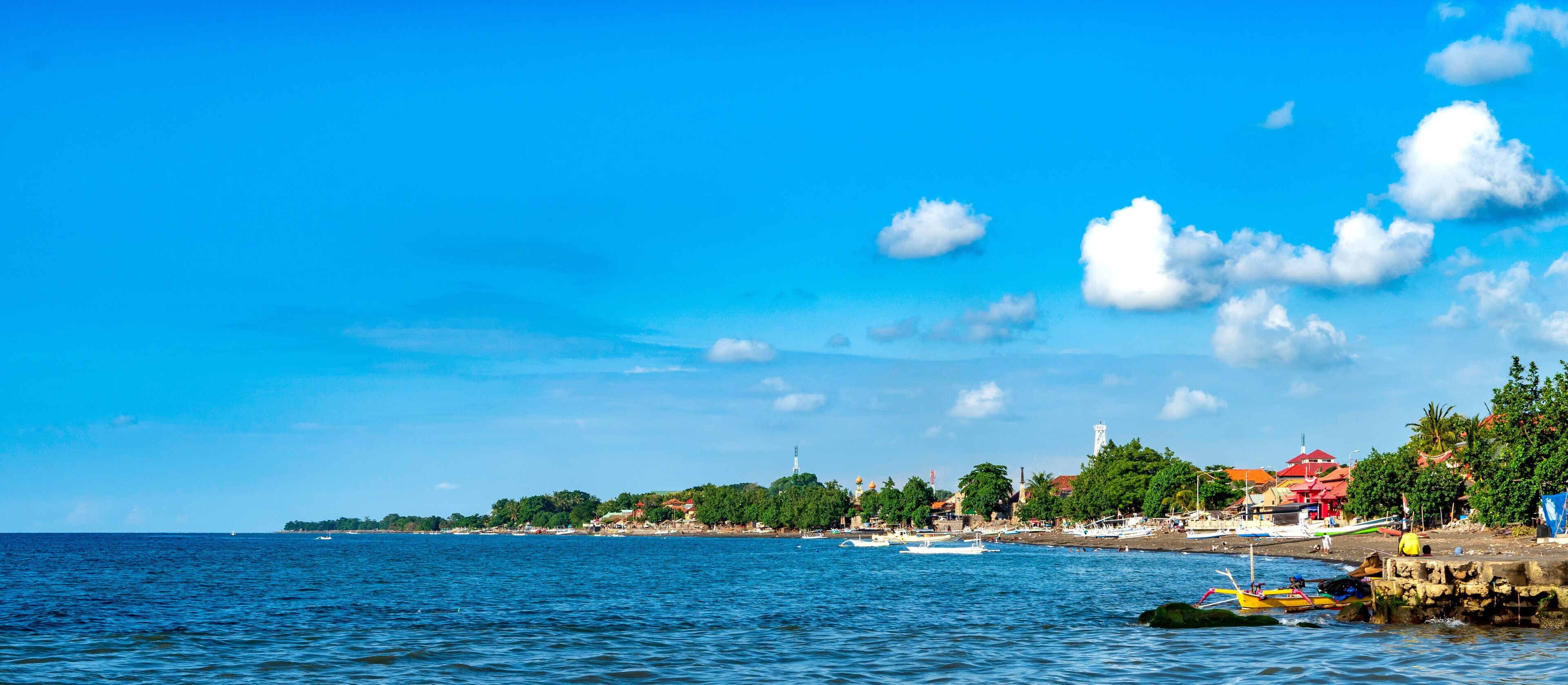 A coastal town with boats, a lighthouse, and a beach.