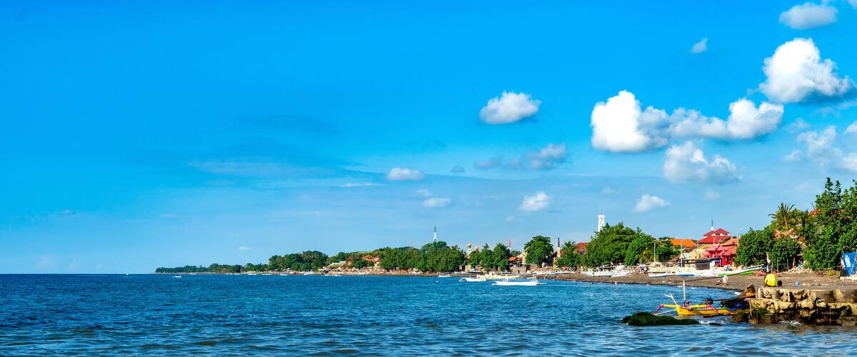 A coastal town with boats, a lighthouse, and a beach.