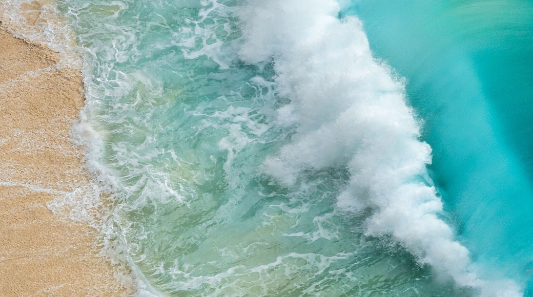 Aerial view of the turquoise ocean crashing against the sandy shore at Bunga Mekar, creating a mesmerizing contrast of colors and textures, Klungkung Regency, Bali, Indonesia.