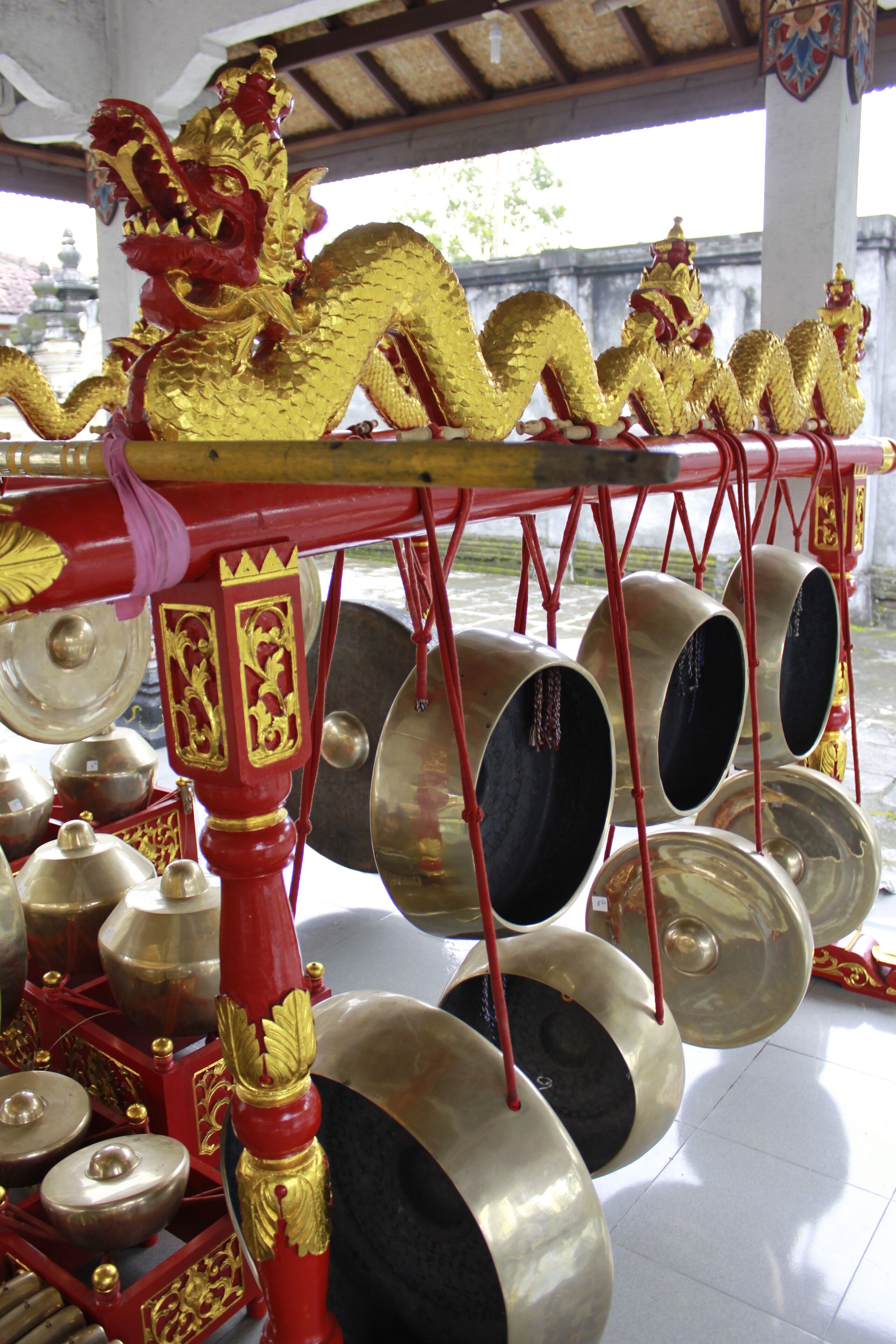 A golden dragon sculpture atop a red and gold structure with multiple hanging bells.