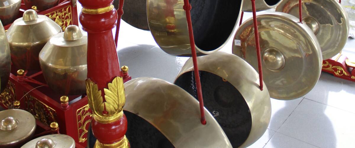 A golden dragon sculpture atop a red and gold structure with multiple hanging bells.