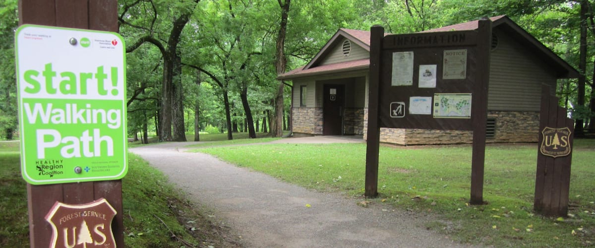 A walking path sign, a small cabin, and a forested area.