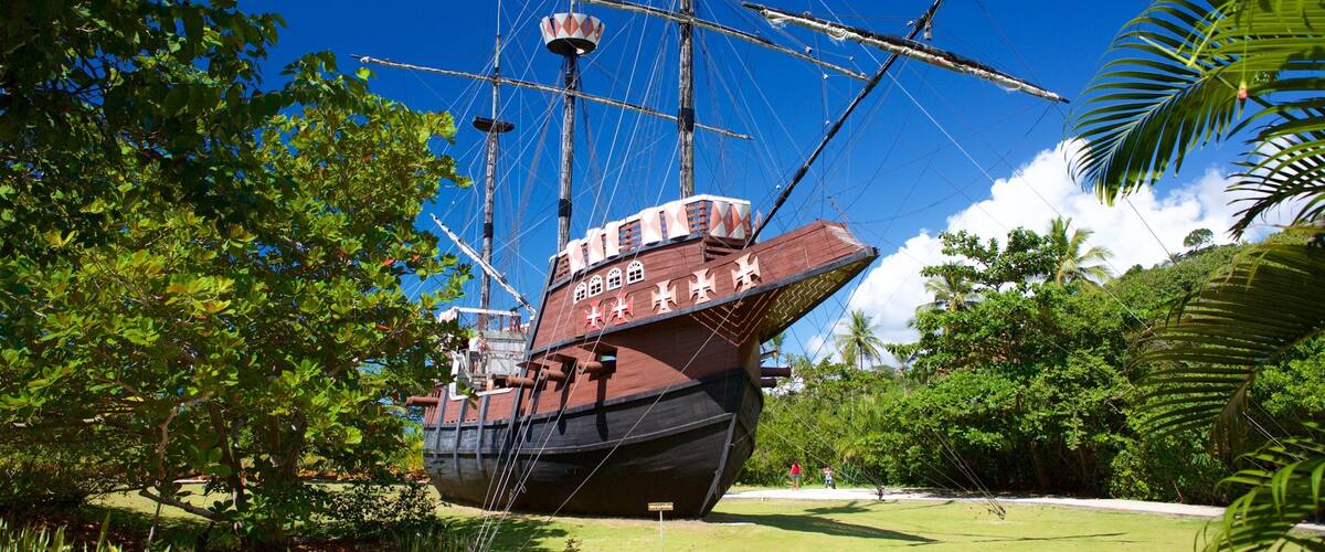 A large ship with the name "HMS Victory" on its side, docked in a lush, green park with palm trees and clear blue skies.