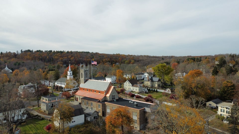 A town with a prominent church, a flag, and autumn-colored trees.