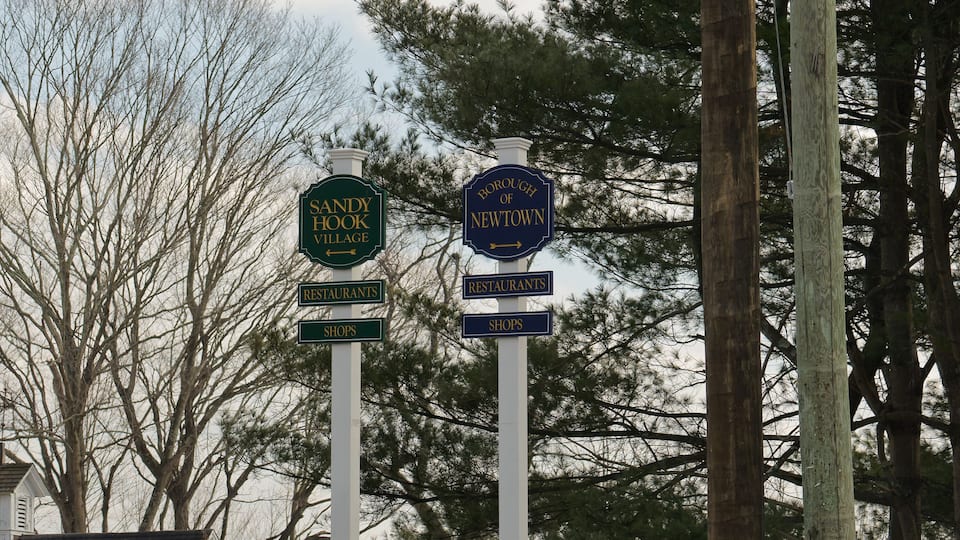 Directional signs for Sandy Hook Village and the Borough of Newtown, pointing towards restaurants and shops.