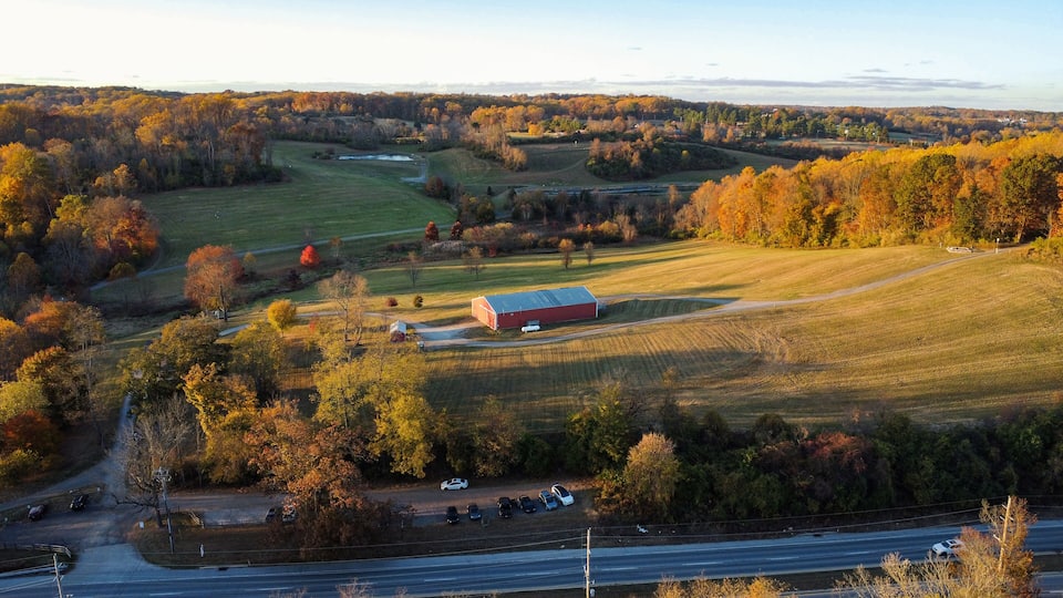A rural landscape with a red barn, fields, and autumn foliage.
