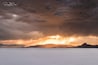Paesaggio innevato con montagne sullo sfondo e cielo nuvoloso.