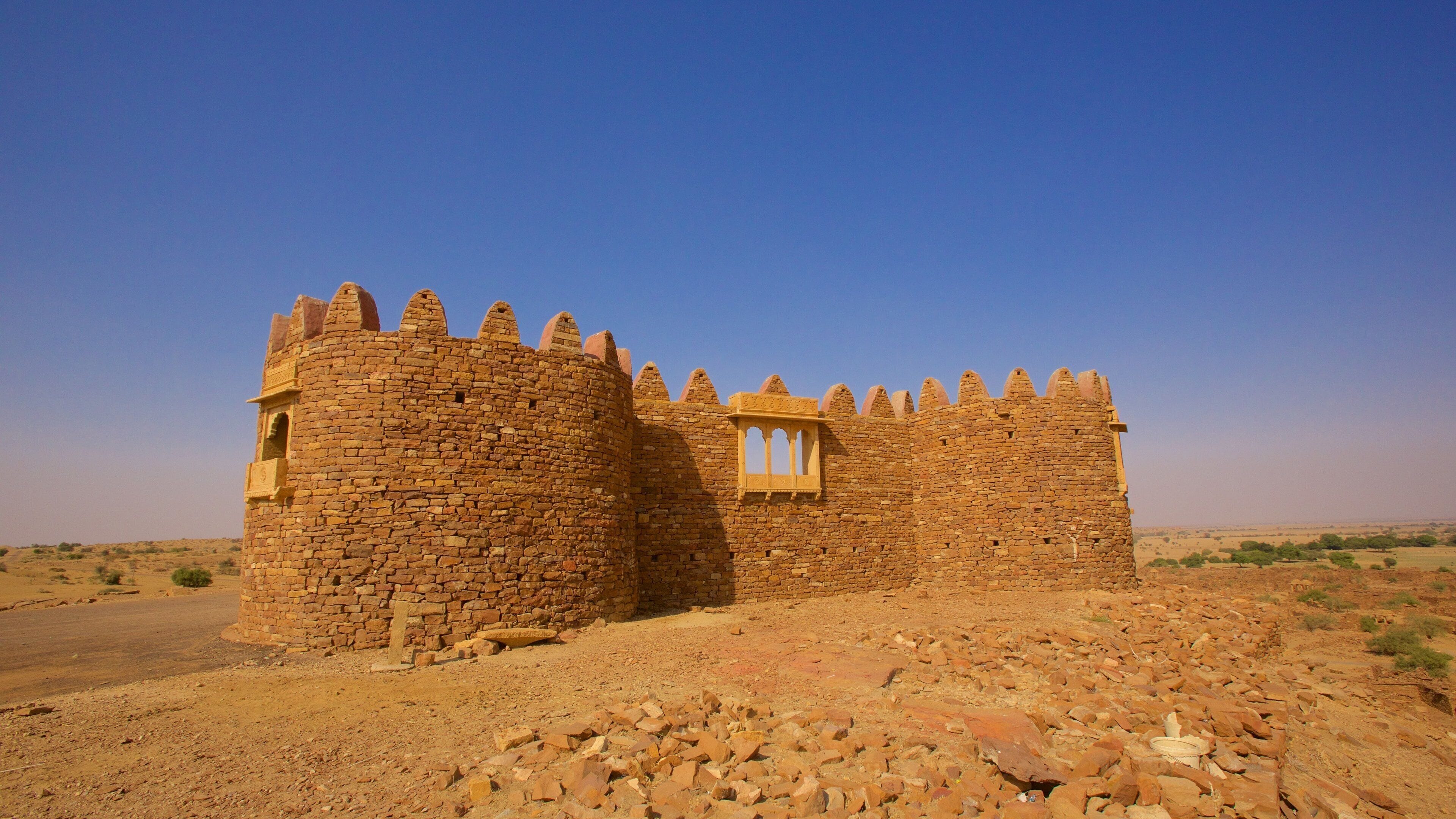 A stone fort with crenellations and a window, set in a desert landscape.