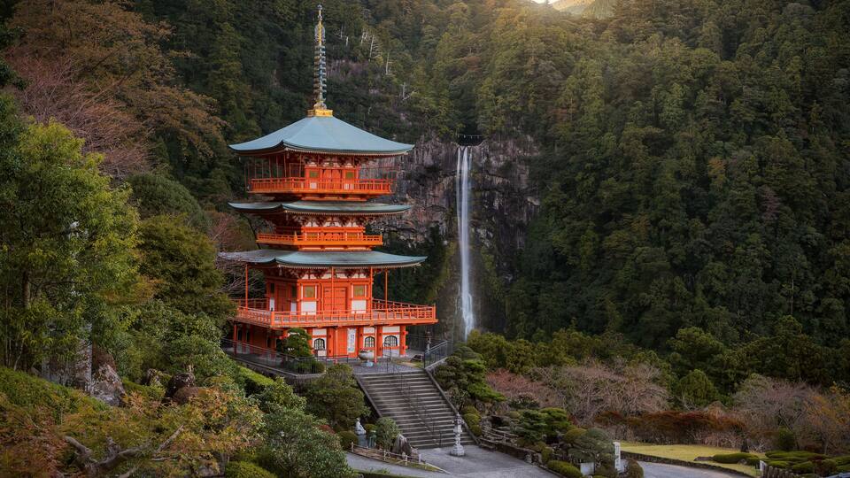 A multi-tiered pagoda with a waterfall in the background.