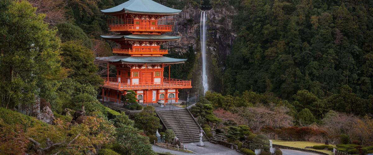 A multi-tiered pagoda with a waterfall in the background.