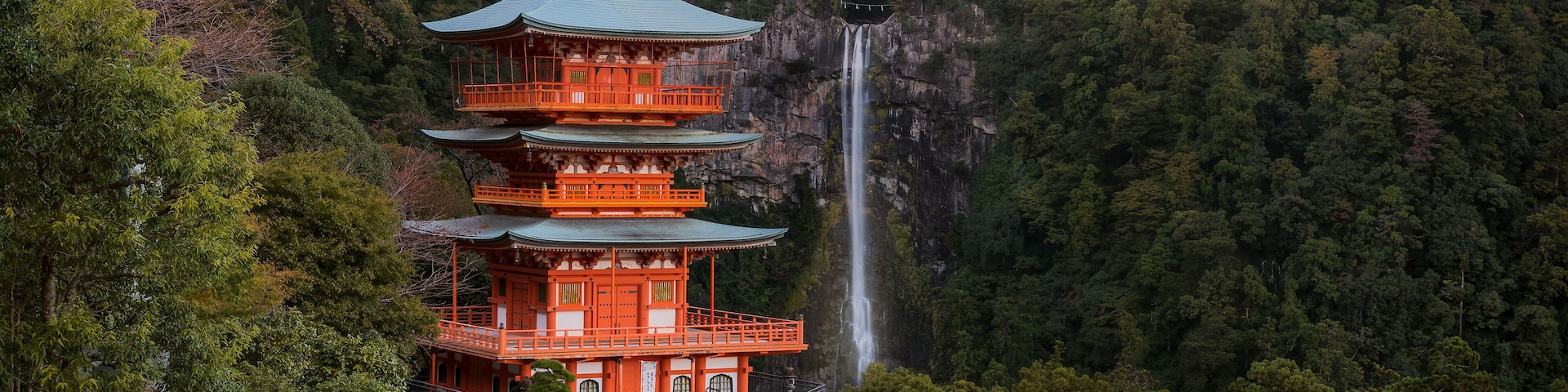 A multi-tiered pagoda with a waterfall in the background.