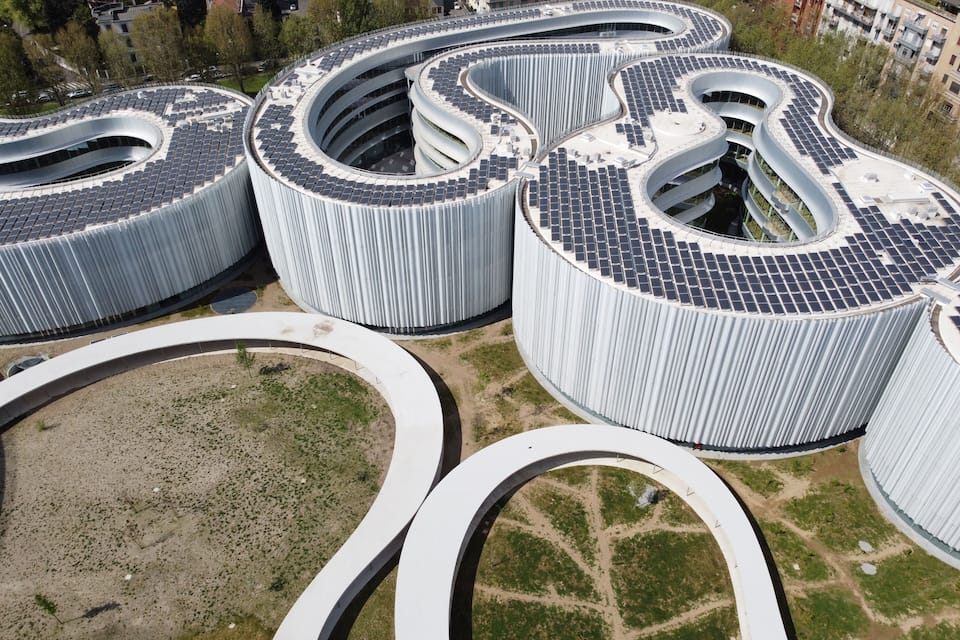 Een modern architectonisch complex met gebogen constructies en zonnepanelen.