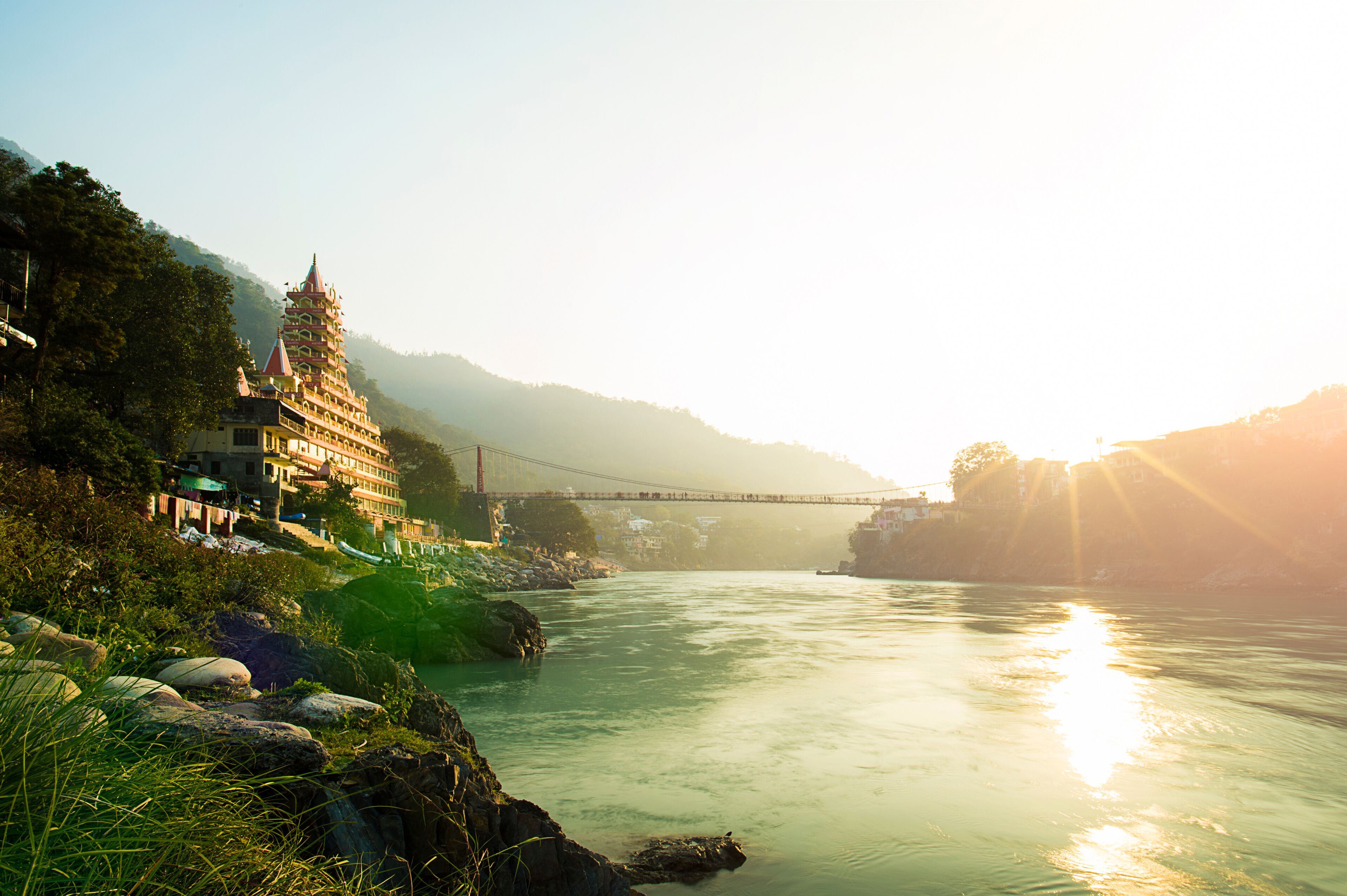 View of Ganga river embankment, Lakshman Jhula bridge and Tera Manzil Temple, Trimbakeshwar in Rishikesh during the sunset. India.