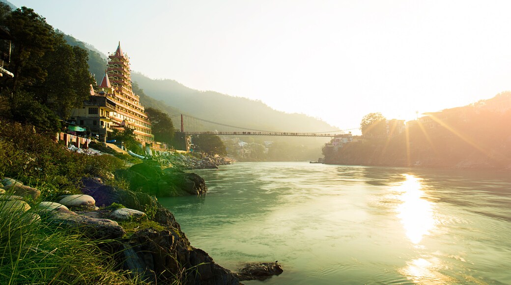 View of Ganga river embankment, Lakshman Jhula bridge and Tera Manzil Temple, Trimbakeshwar in Rishikesh during the sunset. India.