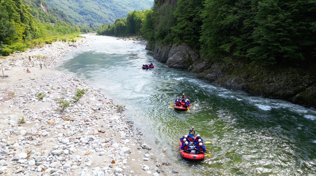 Go rafting on the river with dinghies immersed in the rapids of the stream and the nature of the canyon in Val Sesia Alagna Piedmont Alps mountains - drone view of summer water sport activities