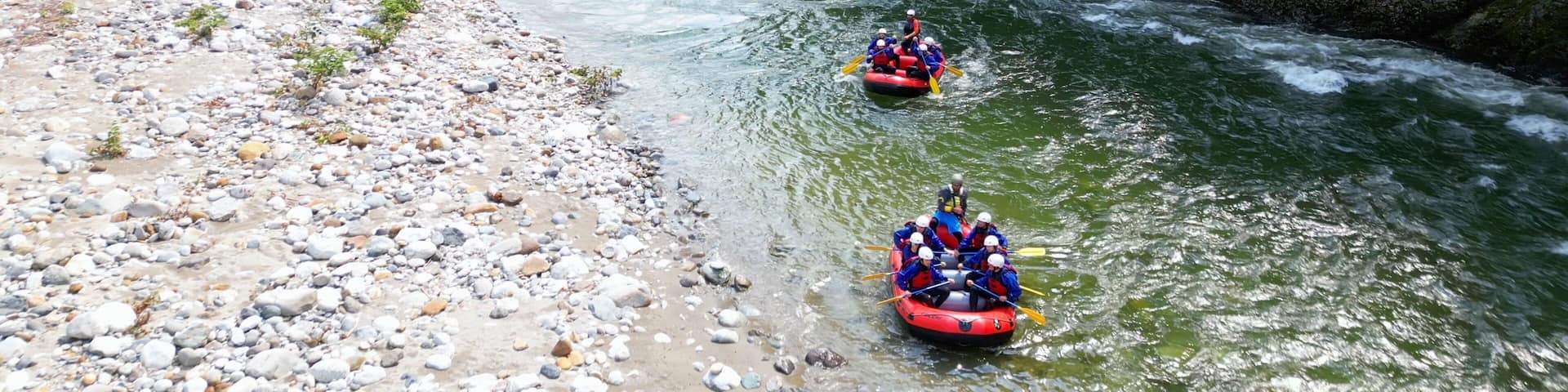 Go rafting on the river with dinghies immersed in the rapids of the stream and the nature of the canyon in Val Sesia Alagna Piedmont Alps mountains - drone view of summer water sport activities