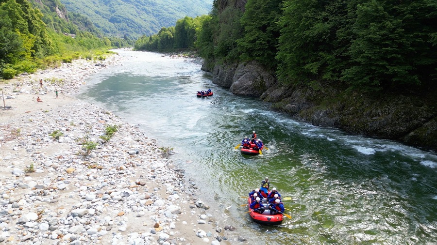 Go rafting on the river with dinghies immersed in the rapids of the stream and the nature of the canyon in Val Sesia Alagna Piedmont Alps mountains - drone view of summer water sport activities