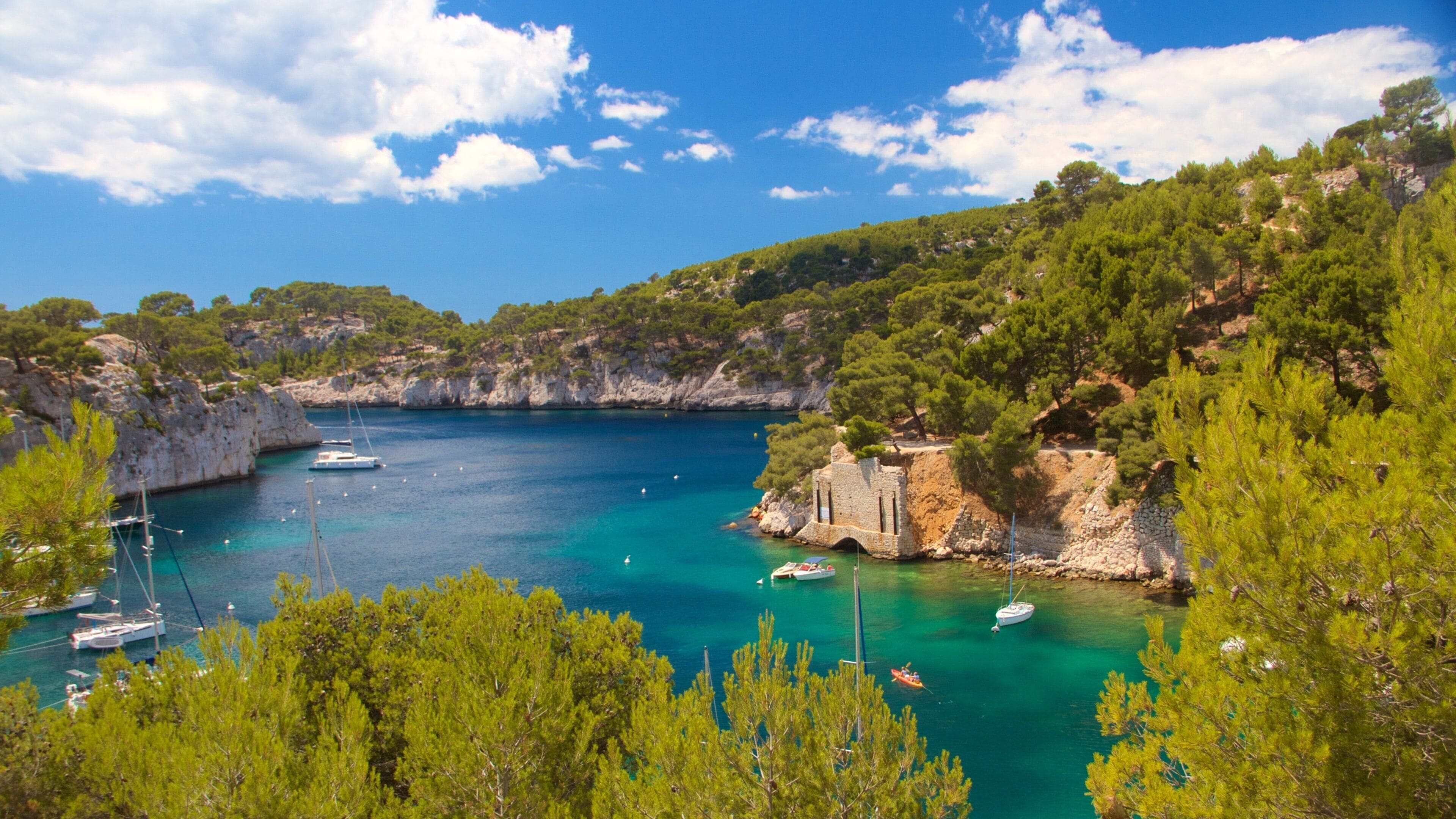 A coastal bay with clear turquoise waters, rocky cliffs, and lush greenery.