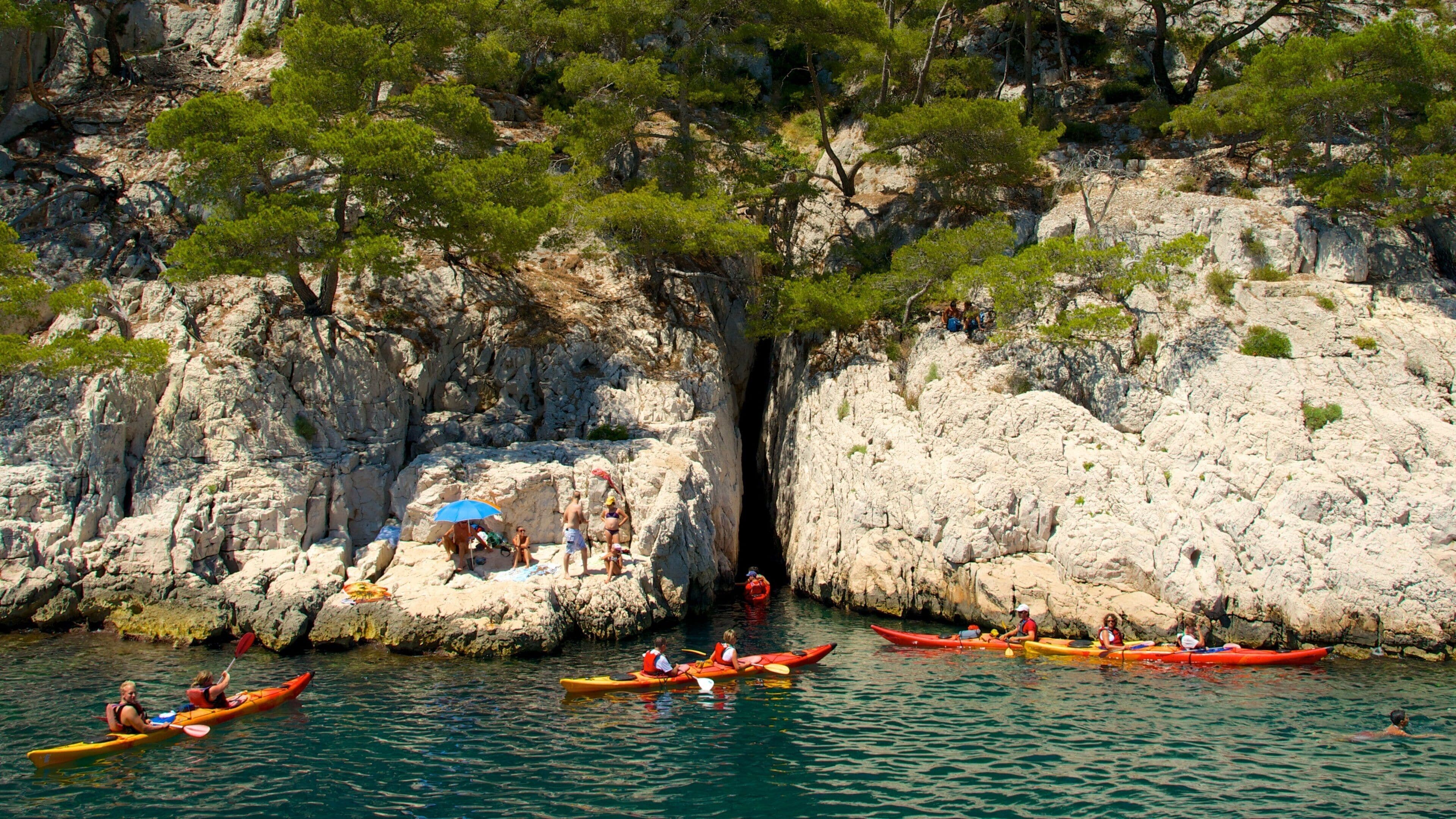 Une zone côtière rocheuse où l’on peut voir des gens faire du kayak et s’asseoir sur les rochers.