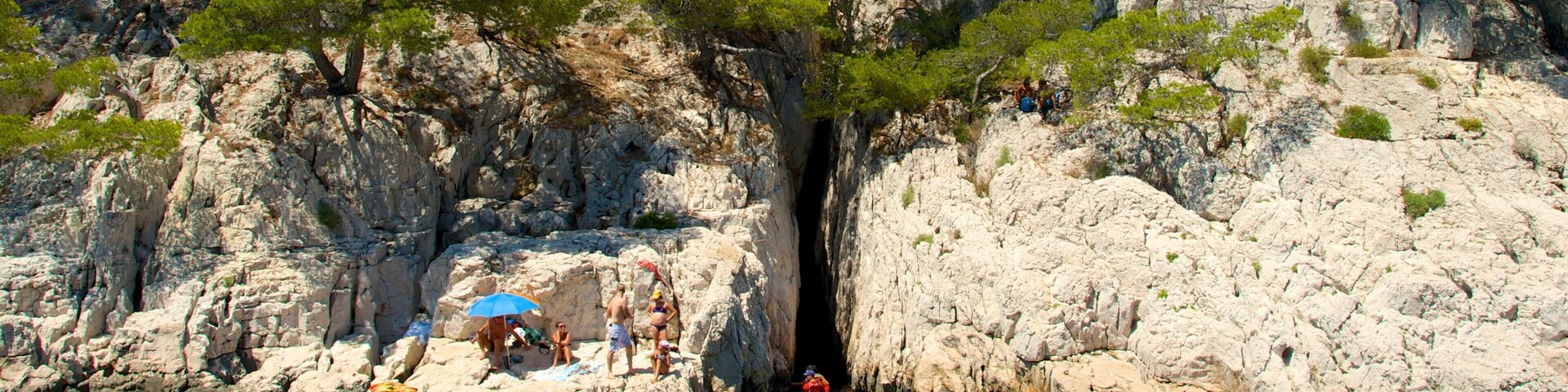 Una zona costera rocosa con gente haciendo kayak y sentada sobre las rocas.