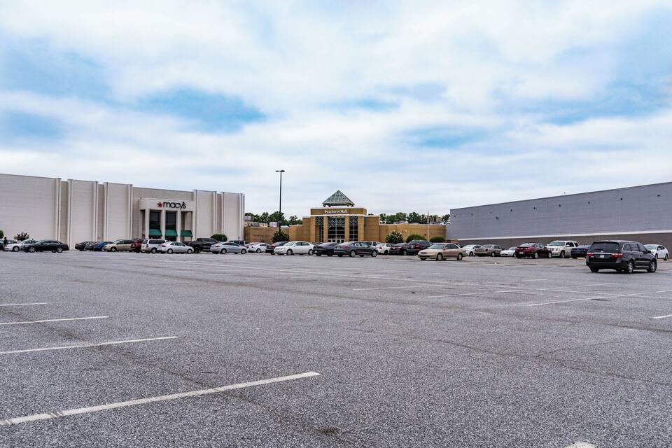 A parking lot with cars, a Macy's store, and a building with a pyramid-shaped roof.