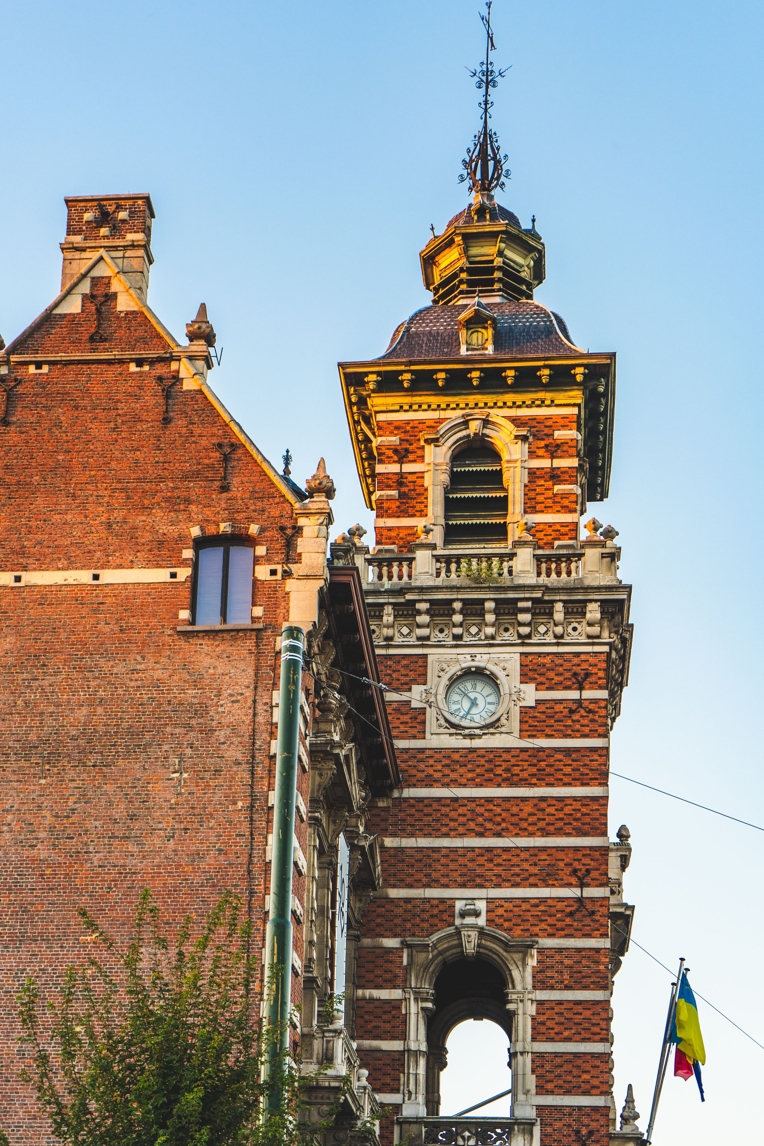 Un edificio histórico con una torre de reloj, muros de ladrillo y detalles arquitectónicos ornamentados.