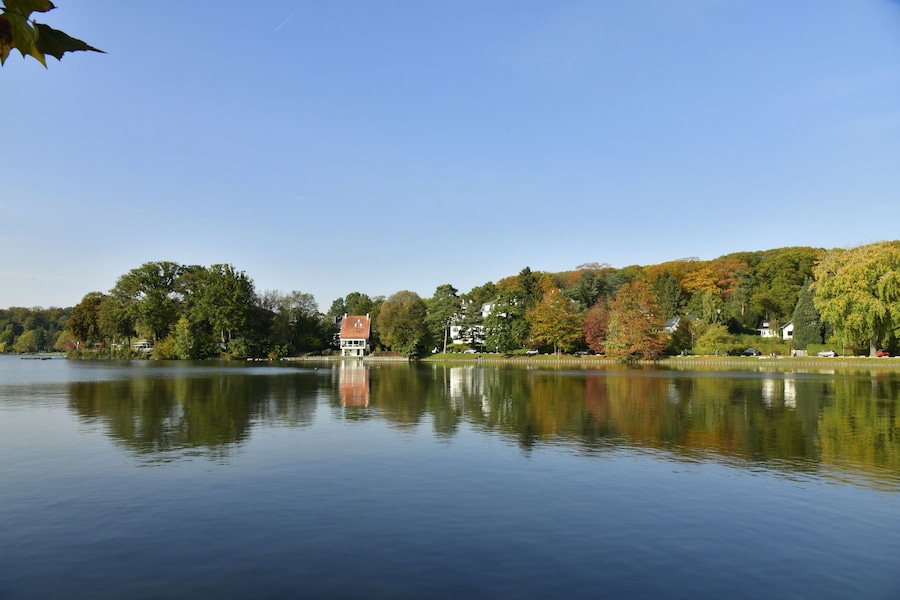 Le lac de Genval dans un cadre bucolique avec ses villas et immeubles à appartements dissimulés dans la nature luxuriante qui l'entoure en automne
