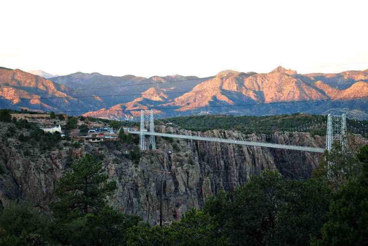 A suspension bridge over a canyon with mountains in the background.