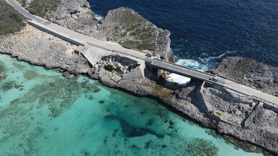 A coastal road bridge with clear turquoise waters and rocky cliffs.
